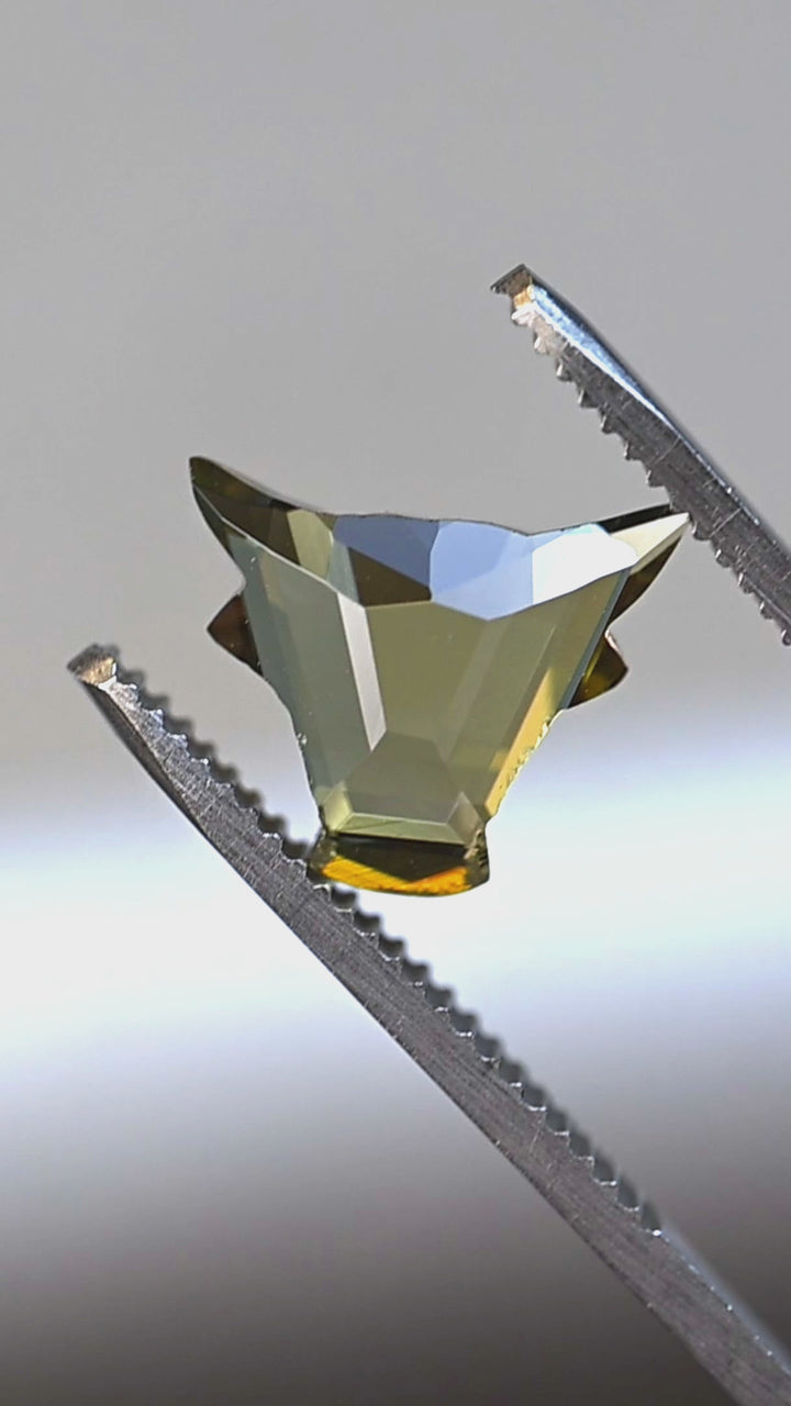 Natural green and yellow Tanzanite rotating in tweezers displaying the precision El Toro cut, brilliance, and untreated color from Tanzania.