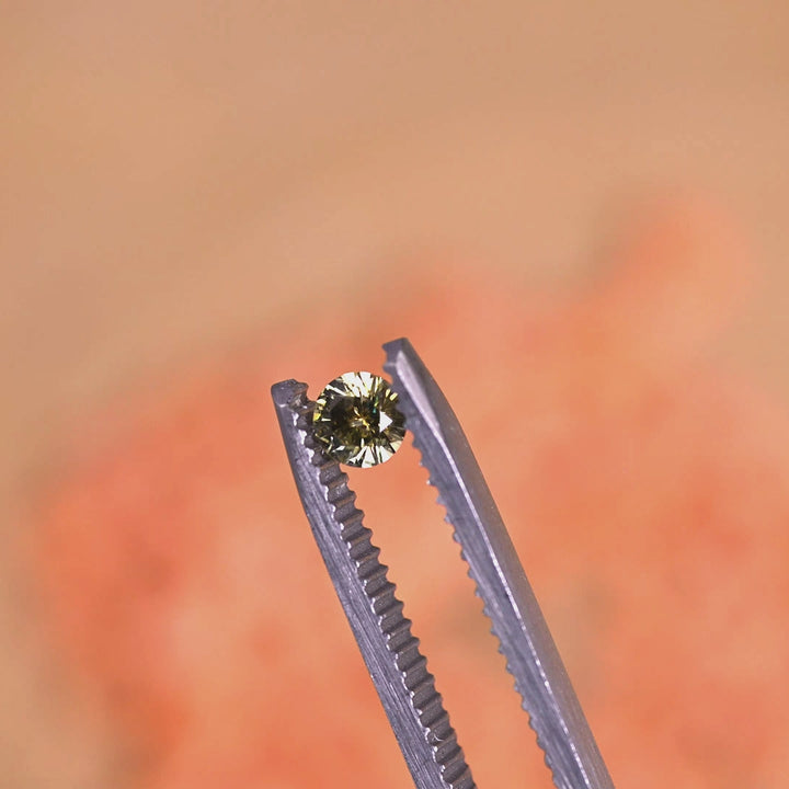 Loose yellow Montana sapphire rotating in tweezers, showing sparkle, color shift and symmetry of the round brilliant cut from Montana.