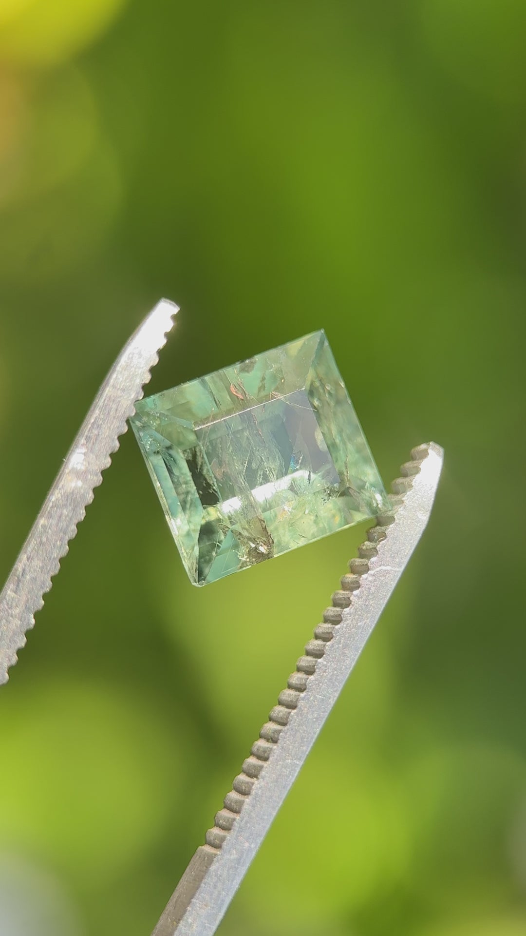 (rotating or angled video): Sparkling teal green carre cut Montana sapphire rotating to show color zoning