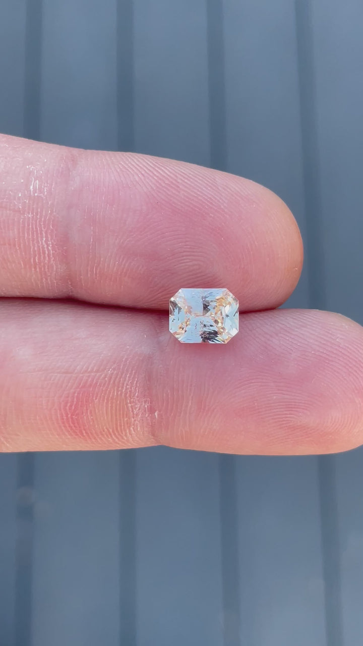 A video capturing the soft peach and champagne hues of a 2.55-carat sapphire under natural lighting. The octagonal mixed cut reveals its clarity and brilliance.