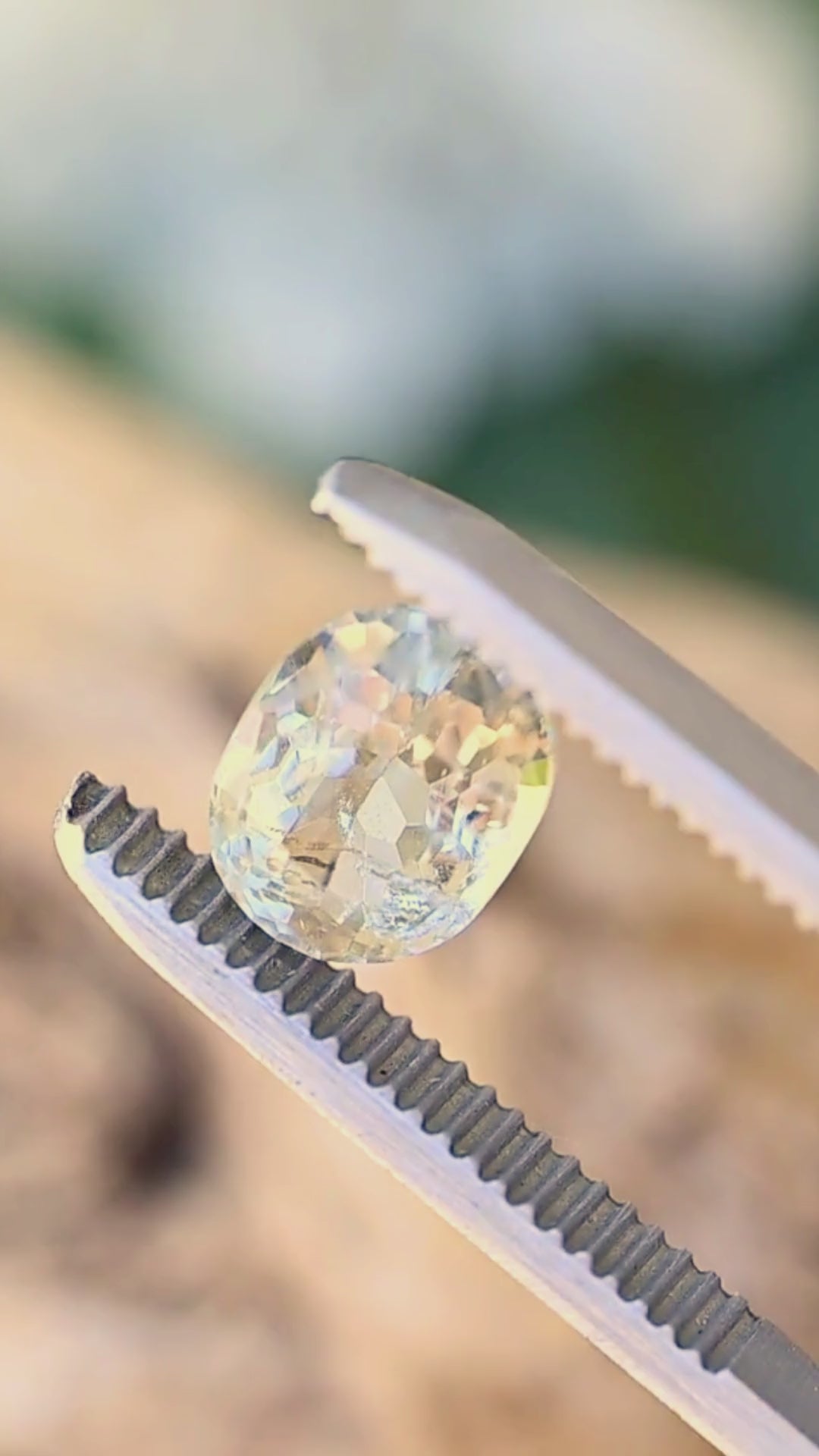 Vintage post-consumer pale yellow tourmaline moving between jeweler’s tweezers, showing the mixed faceting, natural inclusions and soft ivory-to-champagne flashes of the untreated crystal.