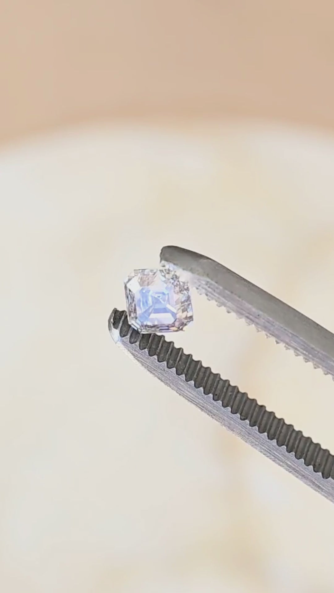 0.90 carat untreated Asscher cut diamond rotated between jeweler’s tweezers, showing its clipped corners, deep step facets and hall-of-mirrors pattern from multiple angles.