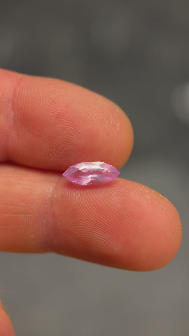 Macro video of 1.50 carat bubblegum pink sapphire resting on fingertip, displaying brilliance, internal reflections, and fine craftsmanship of the precision marquise mixed cut, unheated sapphire from Sakaraha, Madagascar.
