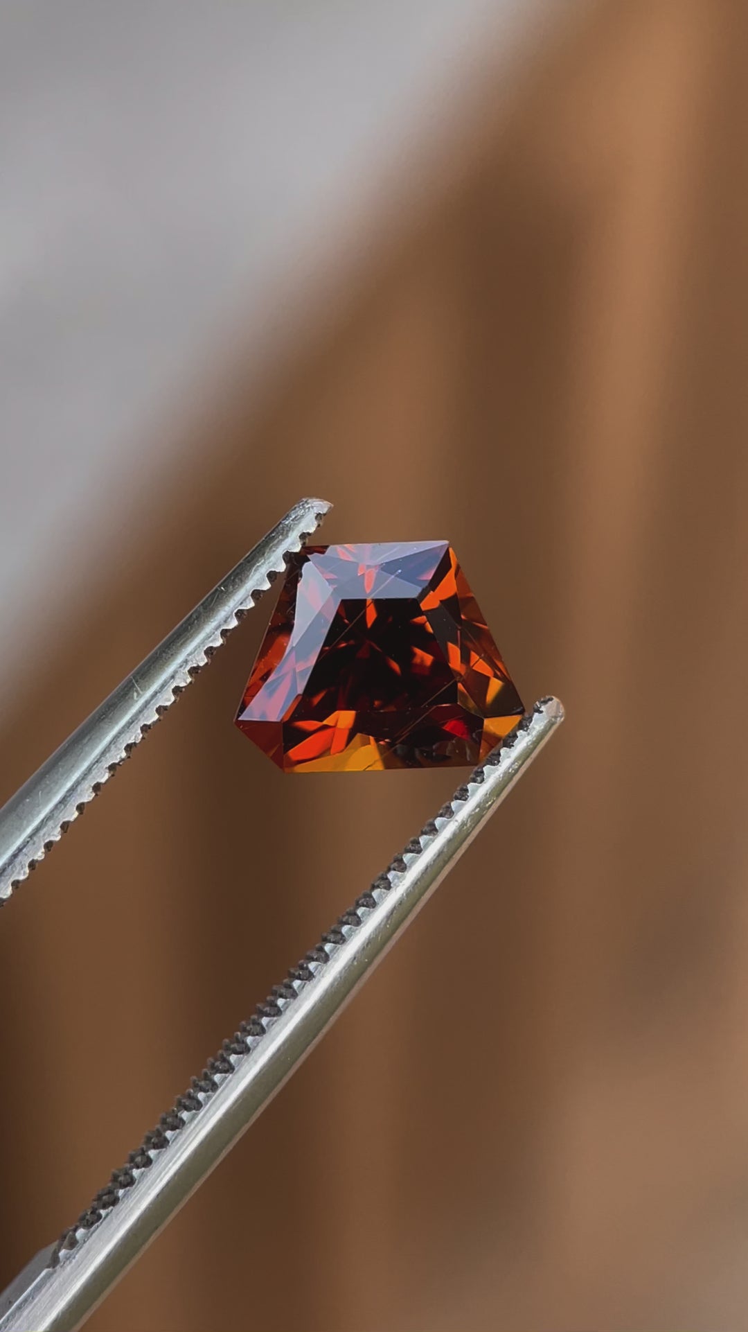 Video capturing the brilliance of a 2.00-carat Hessonite Garnet with a Custom Geometric Shield Cut, highlighting its yellow, orange, and brown tones in natural light.