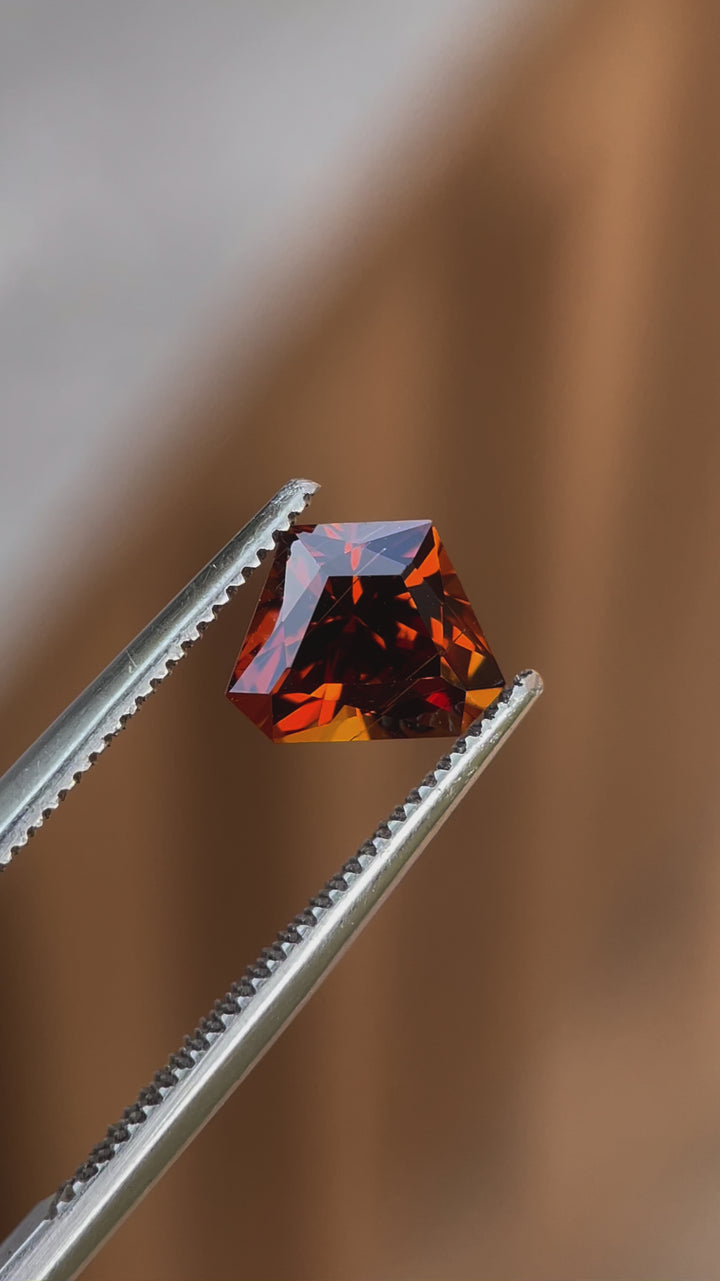Video capturing the brilliance of a 2.00-carat Hessonite Garnet with a Custom Geometric Shield Cut, highlighting its yellow, orange, and brown tones in natural light.