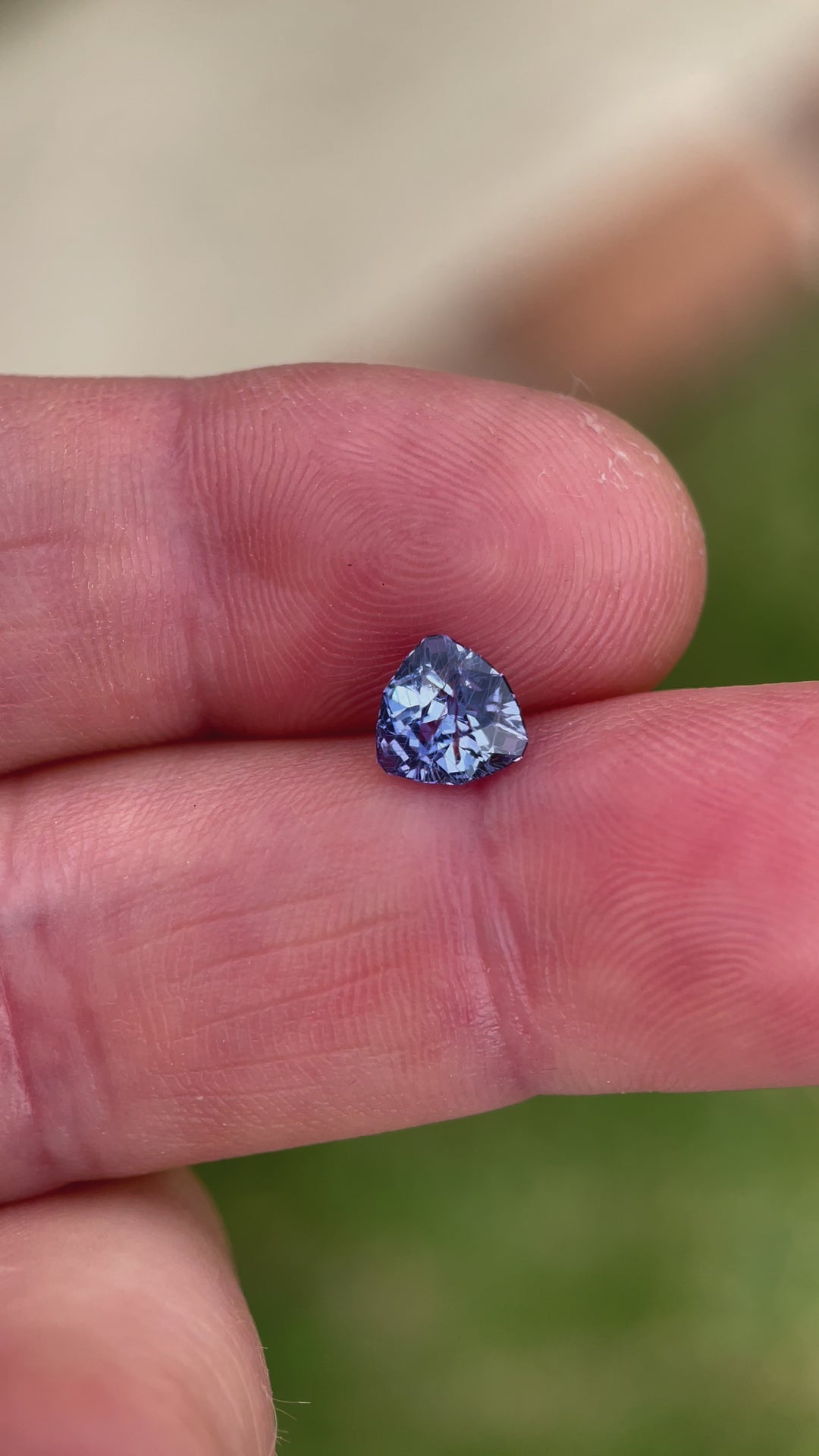 A video showcasing a 1.38-carat sapphire in a custom trillion cut, exhibiting beautiful violet and denim blue hues. The sapphire originates from the Umba River in Tanzania, untreated, with sharp facets and a brilliant luster reflecting the natural light.