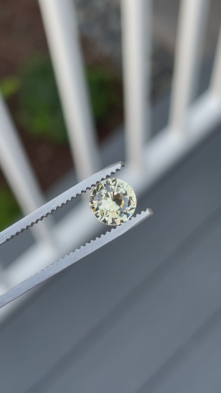 360-degree close-up video of a 1.59-carat round brilliant peach yellow sapphire from Sri Lanka, revealing its fiery sparkle and precision cut.