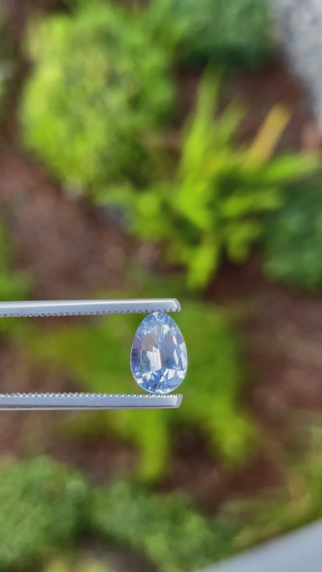 A close-up video of a 1.74-carat Ceylon denim blue sapphire, showing the sparkle of its custom Poval cut under daylight. The gemstone's natural brilliance and untreated nature are visible, with its dimensions measuring 9.18mm in length, 6.38mm in width, and 3.82mm in height, sourced from Sri Lanka.