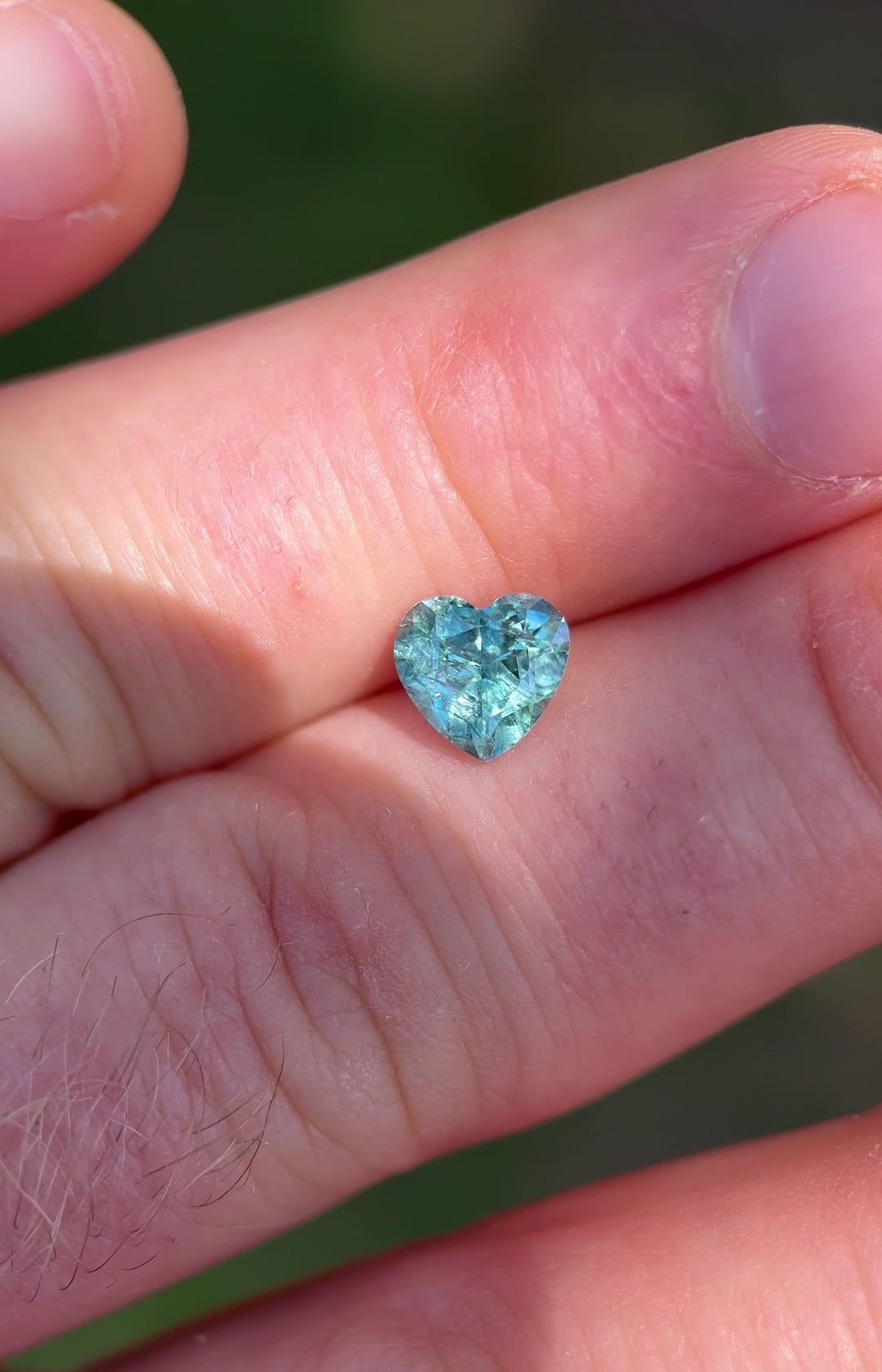 Close-up motion video of heated Montana sapphire, heart cut, with brilliant teal-green color play.