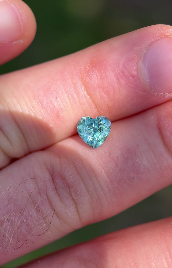 Close-up motion video of heated Montana sapphire, heart cut, with brilliant teal-green color play.