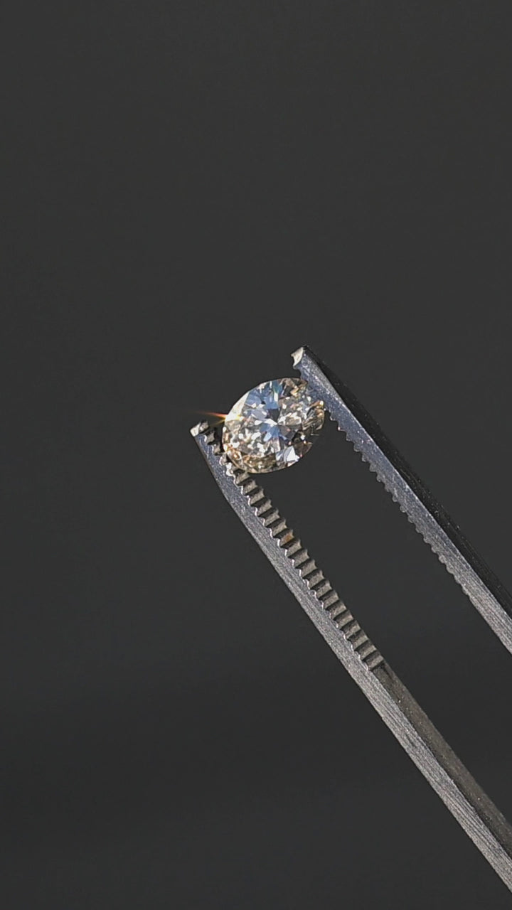 1.02ct natural champagne oval brilliant cut diamond from Canada rotating in gem tweezers under direct sunlight showing off color and sparkle.