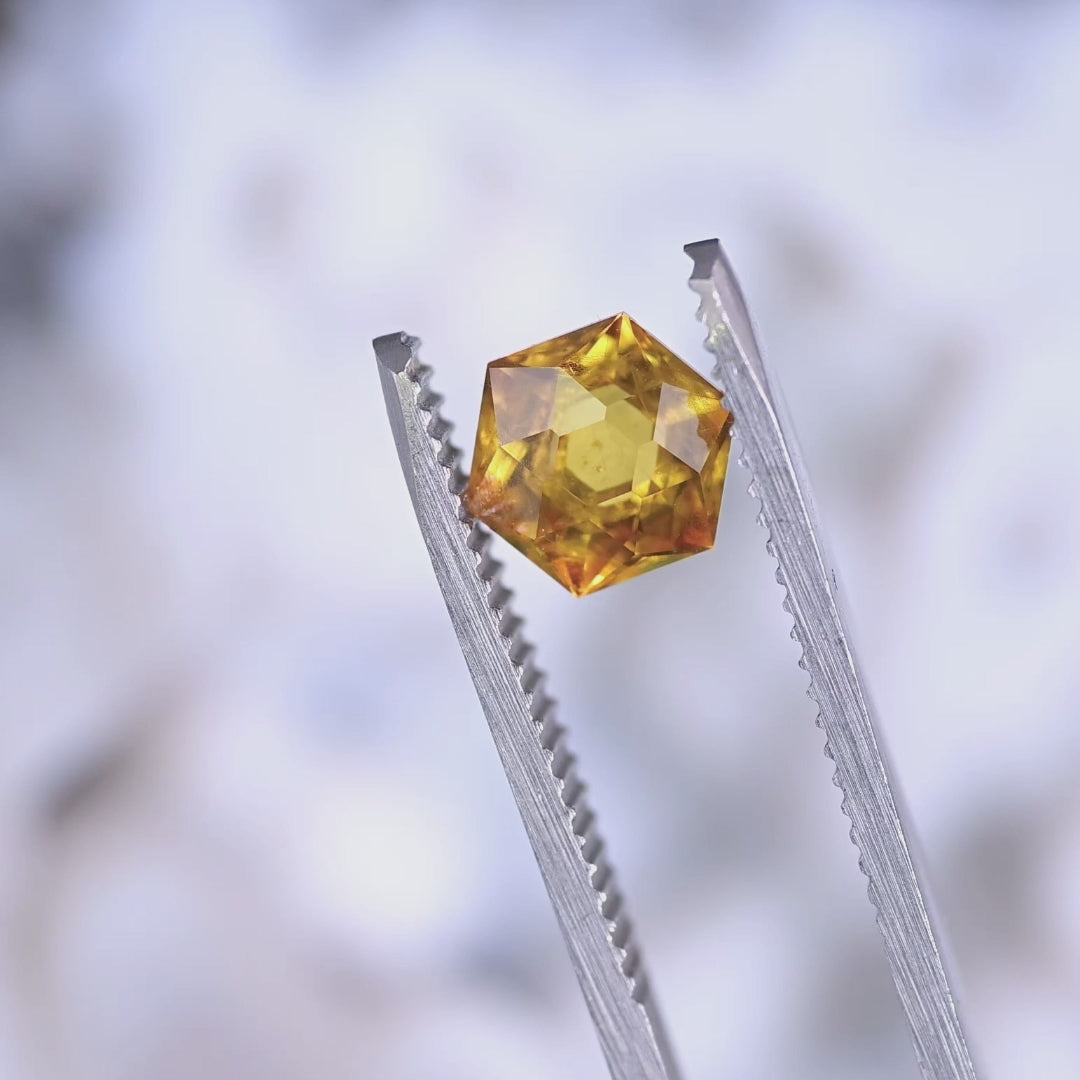 Video of 1.88ct orange yellow Montana sapphire hexagonal modified brilliant cut rotating under light to show brilliance, facet symmetry and heated golden glow