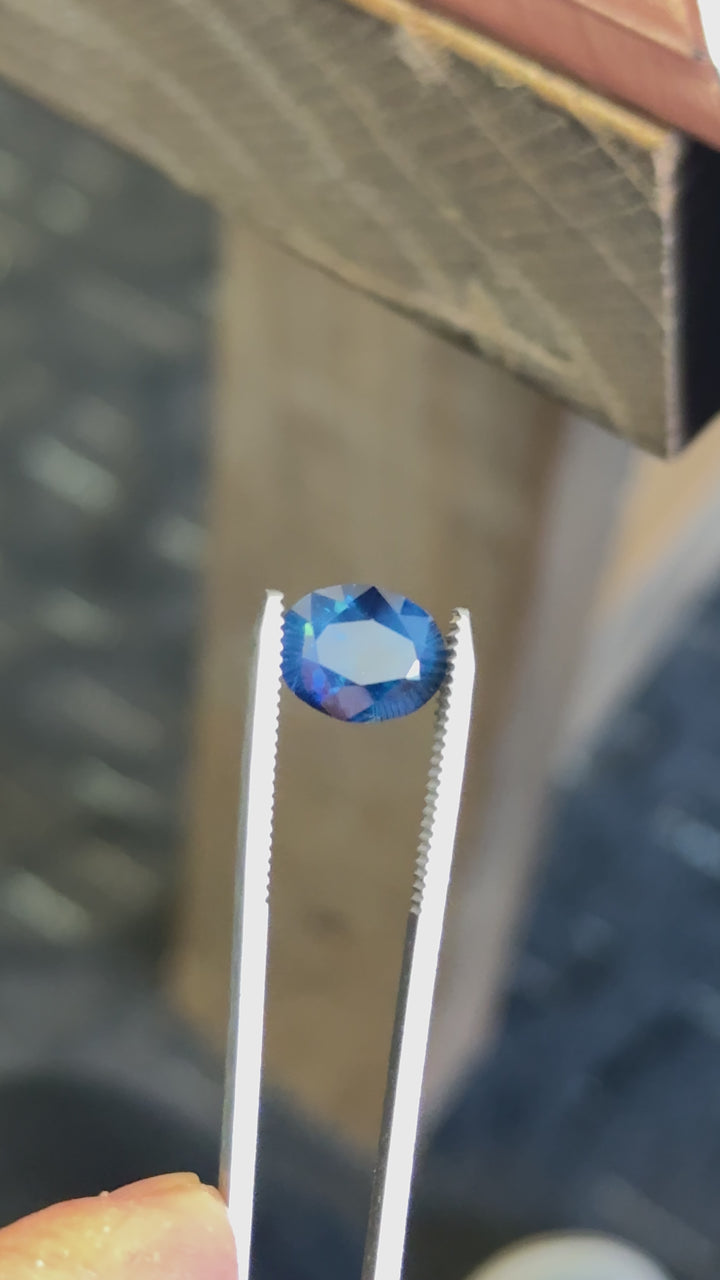 Close-up of royal teal Nigerian sapphire in motion, emphasizing saturated body color and dynamic blue-green reflections.