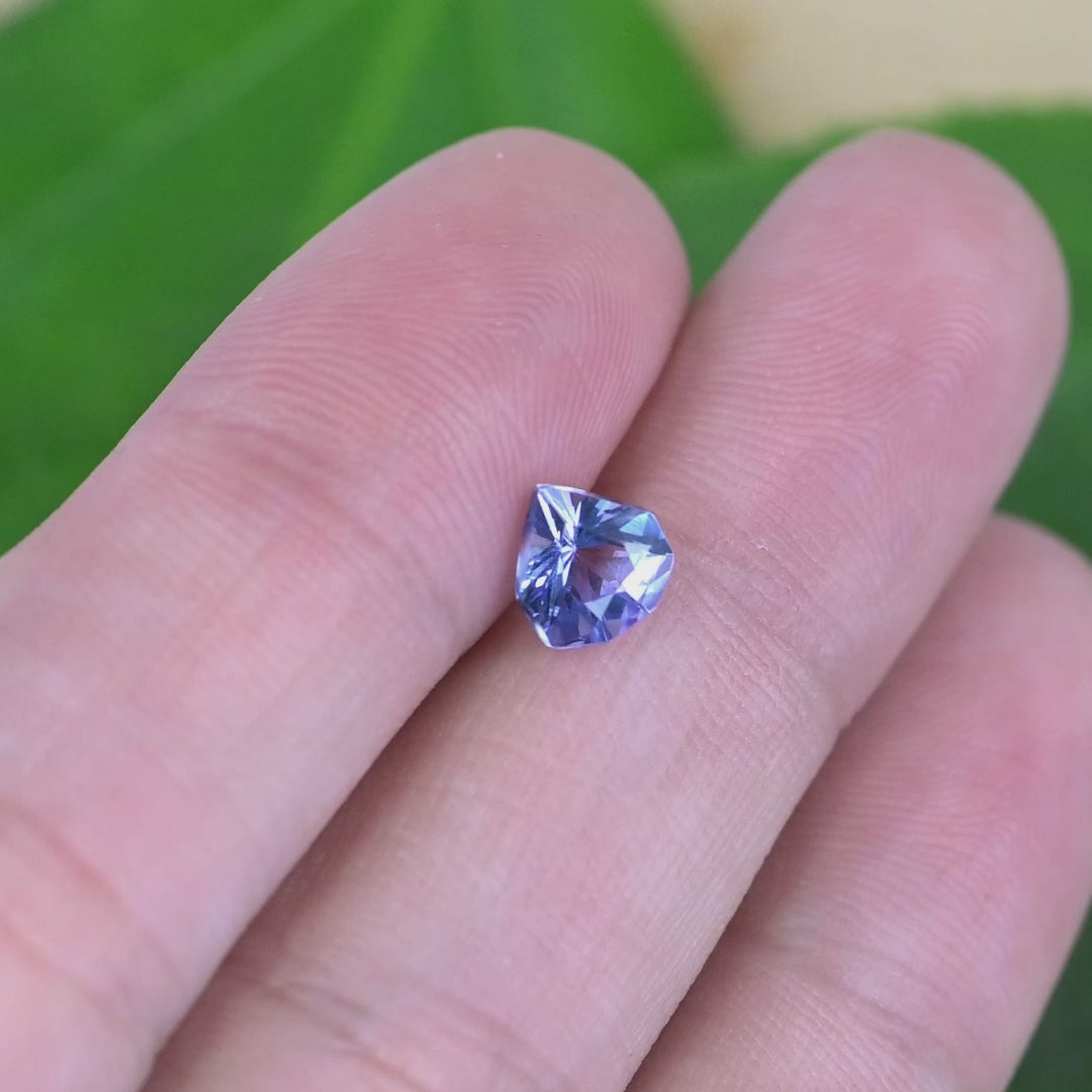 Loose periwinkle violet tanzanite from Tanzania displayed on a hand showing the size and brilliance of the custom geometric shield cut gemstone.