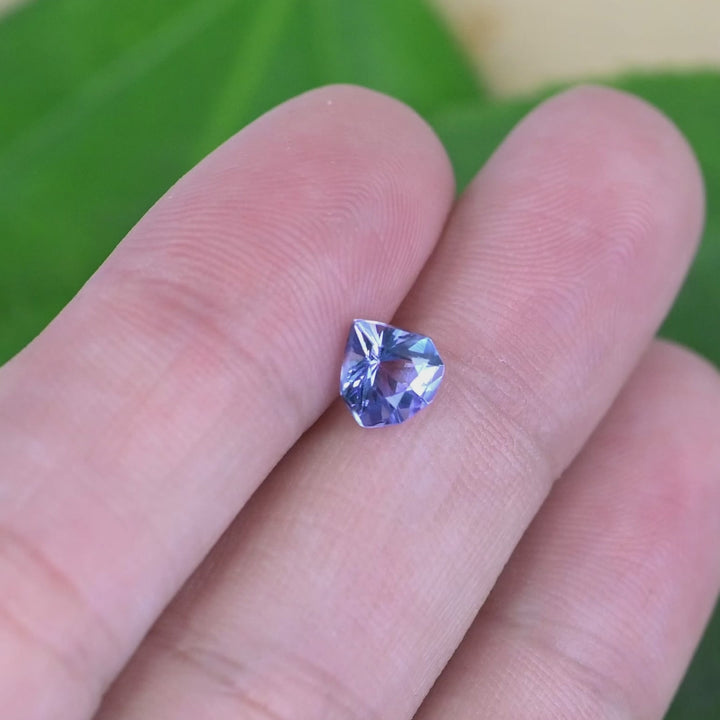 Loose periwinkle violet tanzanite from Tanzania displayed on a hand showing the size and brilliance of the custom geometric shield cut gemstone.