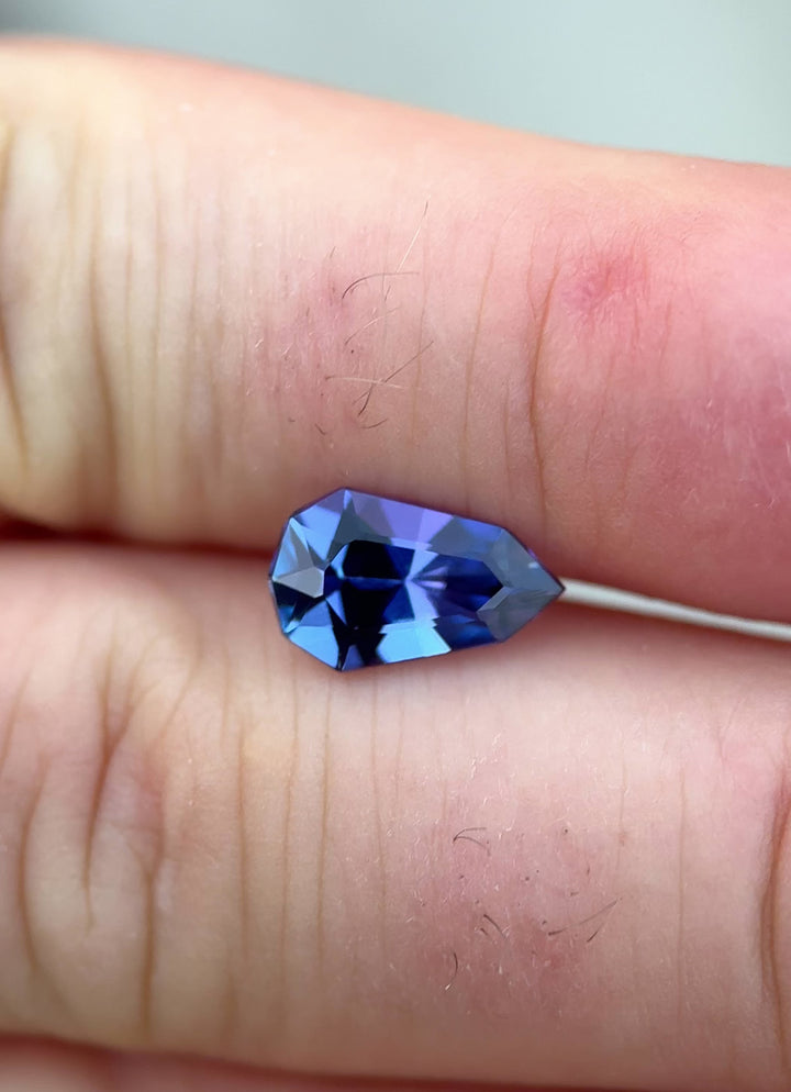 Macro video of 2.42CT Tanzanite from Merelani Hills, Tanzania, highlighting precision shield mix faceting and dynamic flashes of blue, purple, and green hues as the gem moves in sunlight.