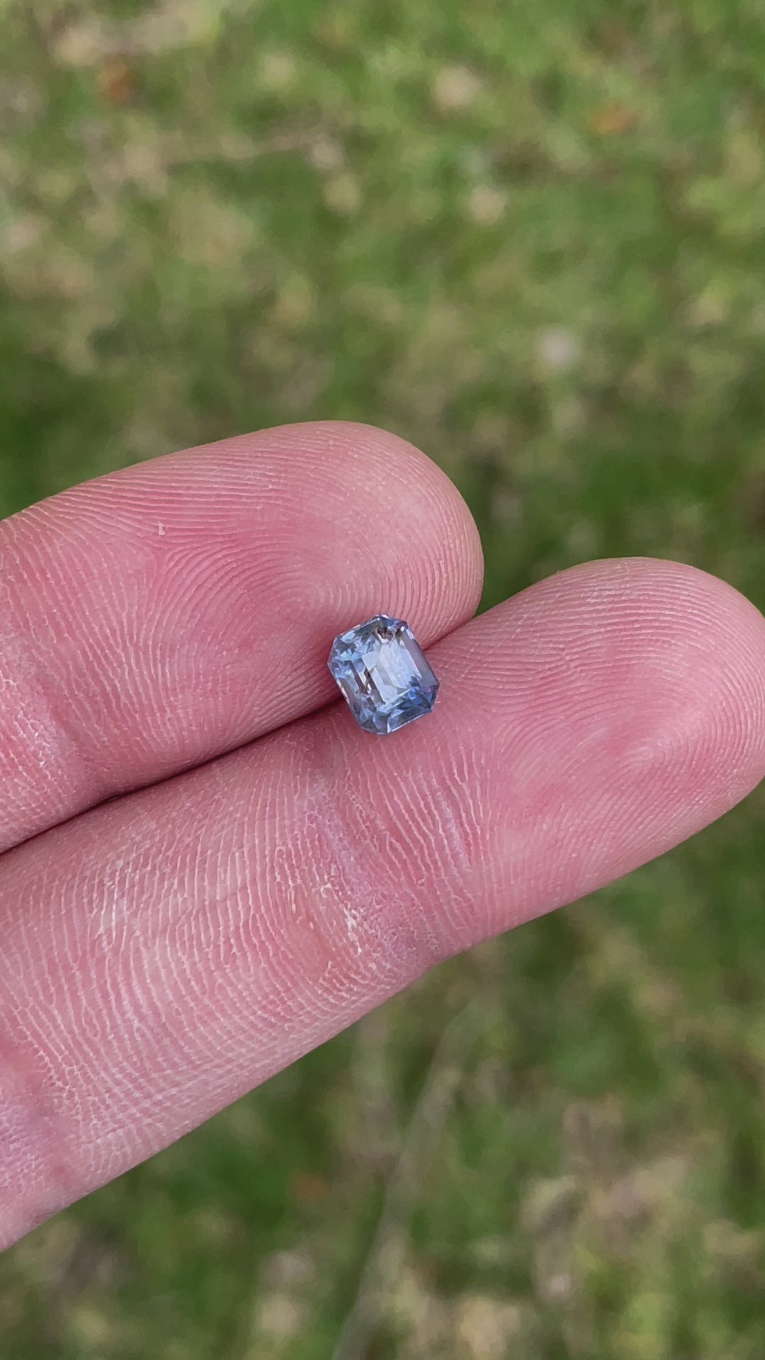 Visual presentation of a bi-color sapphire, focusing on its unique lavender and blue colors and emerald cut. This video provides a close-up look at the gemstone's structure and natural brilliance, highlighting its Tanzanian origin and the absence of any treatments.