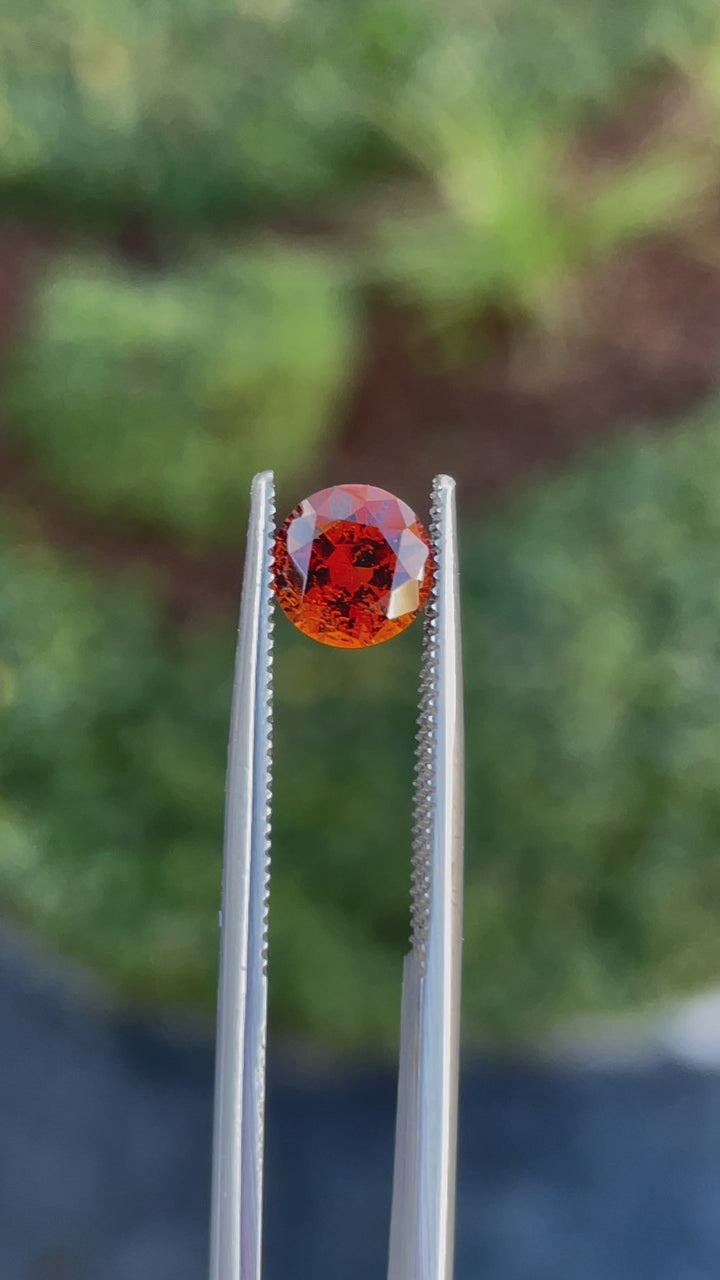 Video highlighting a round brilliant cut 1.25-carat Hessonite Garnet with orange and brown shades, untreated and sourced from Kenya.