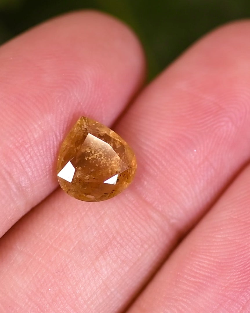 Macro video of 2.17 carat yellow brown orange sapphire turning slowly, capturing brilliant light play and internal reflections through its custom wide pear cut, untreated sapphire from Umba River, Tanzania.