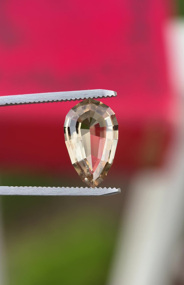 Rotating daylight video of 5.36 carat champagne brown tourmaline from Congo, Africa, showing geometric pear step cut brilliance, crisp facet reflections, and untreated golden-brown tones.