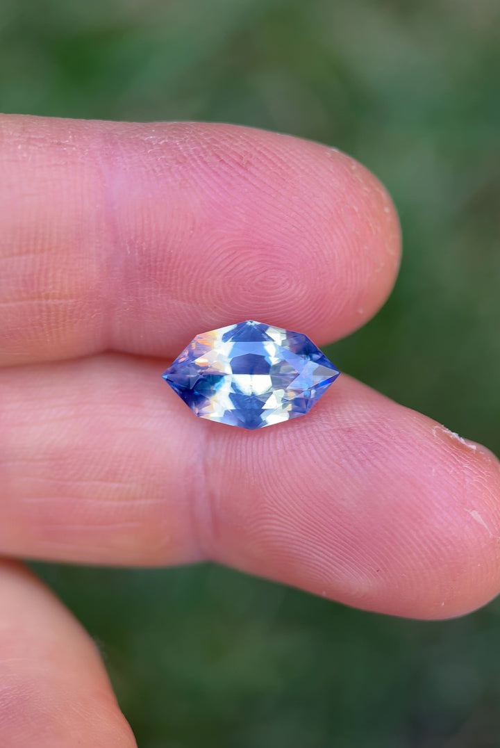 Close-up video of 5.00 carat blue and white parti sapphire resting on natural bark, capturing brilliance, clarity, and opalescent flashes of the precision marquise mixed cut, untreated sapphire from Madagascar.
