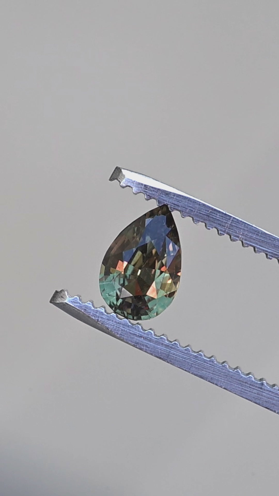 Madagascar color change alexandrite pear cut rotating in tweezers under changing light
