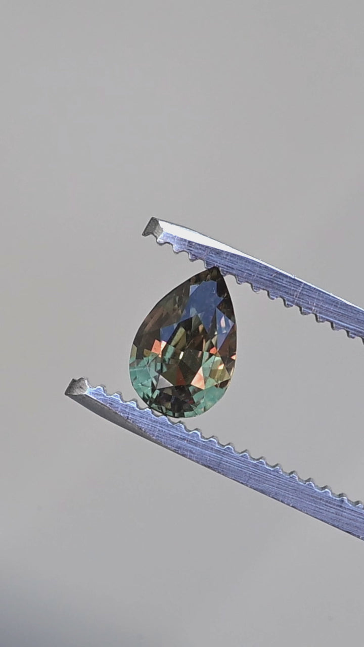 Madagascar color change alexandrite pear cut rotating in tweezers under changing light