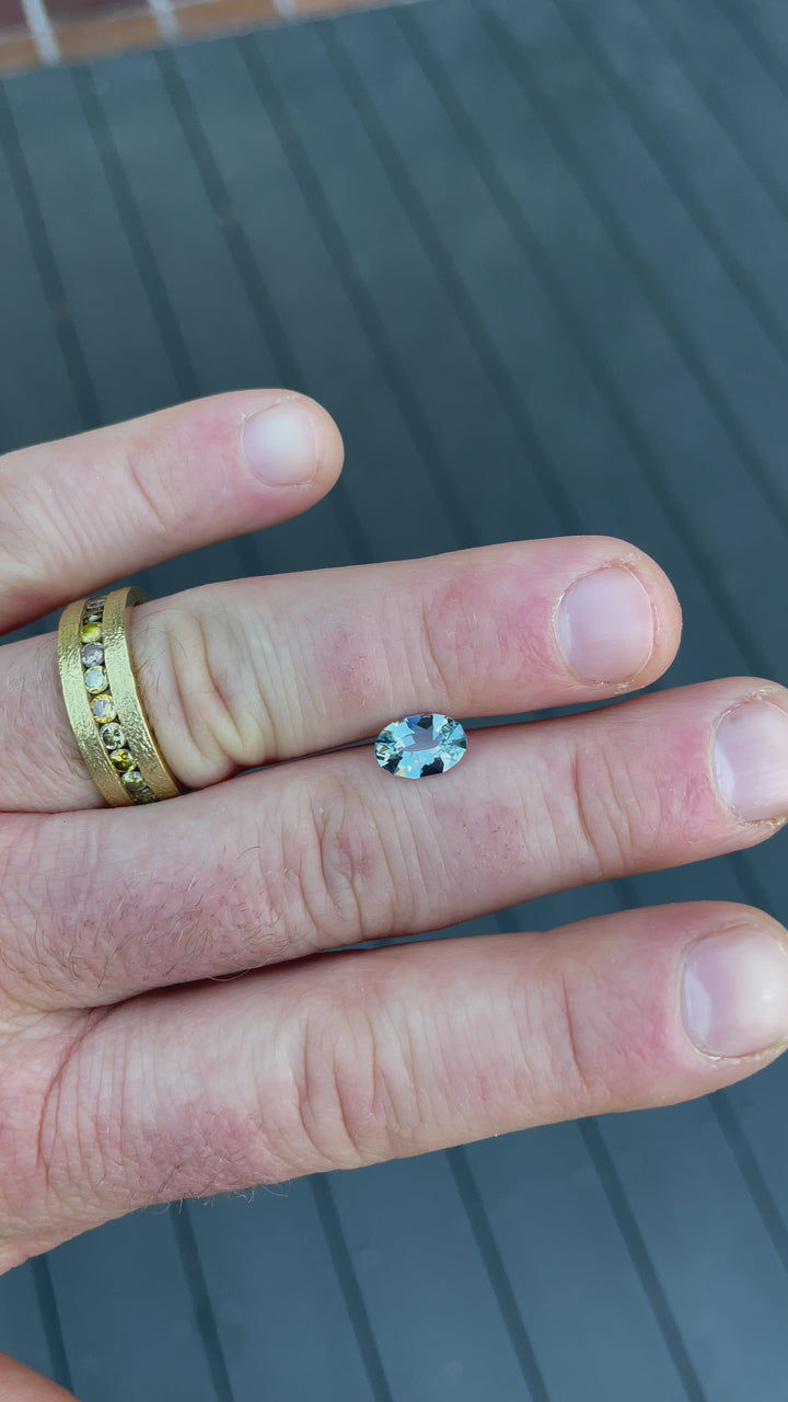 A 1.61-carat seafoam blue sapphire in oval mix brilliant cut, showcased in natural light to highlight its brilliance and vivid color.