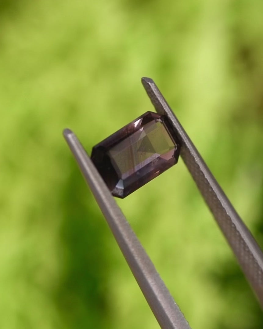 Video of 1.34CT purple violet eggplant sapphire turning in tweezers, capturing reflections and color transitions across its modified emerald cut, unheated sapphire from Umba River Valley, Tanga, Tanzania.