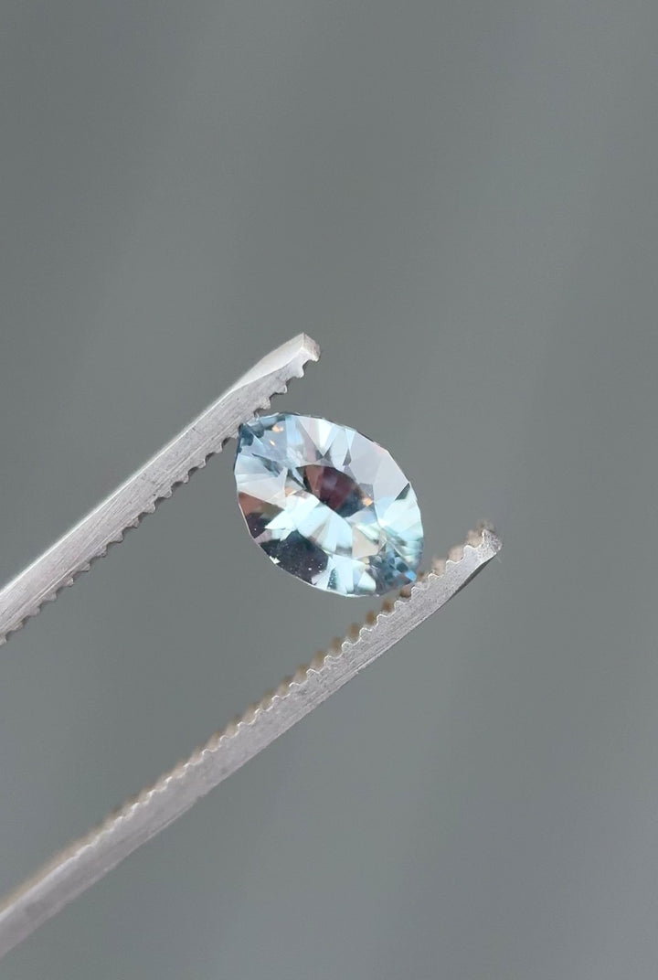 Video of 1.58CT teal, blue, and green sapphire rotating in gemstone tweezers under natural light, highlighting brilliance, color shifts, and fine faceting of the precision marquise mixed cut, unheated sapphire from Sakaraha, Madagascar.