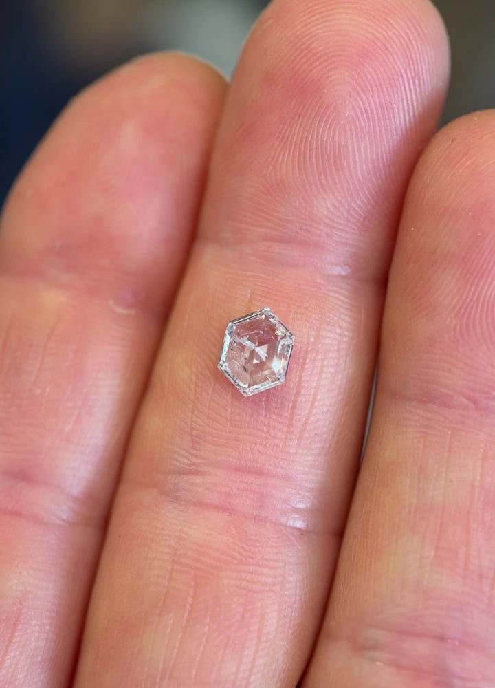 Close-up video of a natural 1.01 carat hexagonal step cut diamond from Gahcho Kué, Canada, showing the brilliance and pattern play of its geometric faceting under diffused daylight.