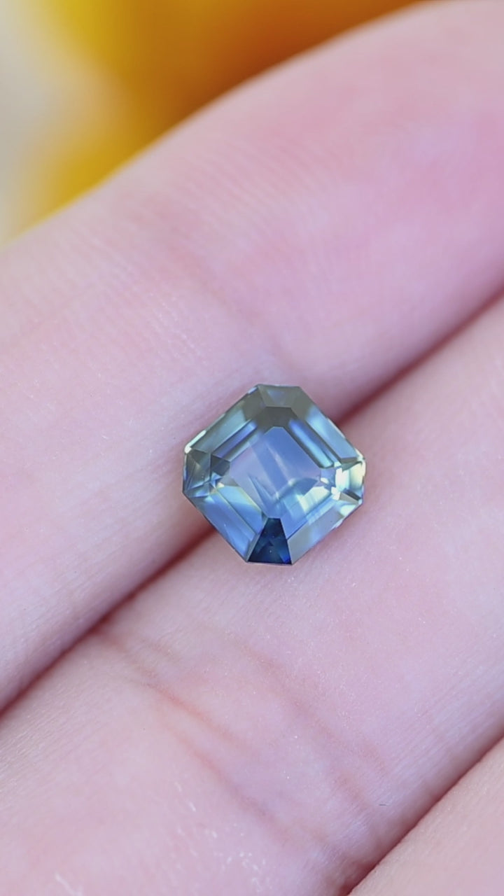 2.06ct natural parti blue green yellow Asscher cut sapphire shown in hand under natural light