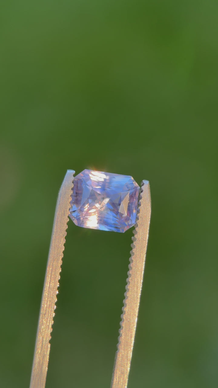 Video of a 2.70-carat radiant cut sapphire in lavender, violet, and blue tones from Sri Lanka, rotating under natural light to show its brilliance.