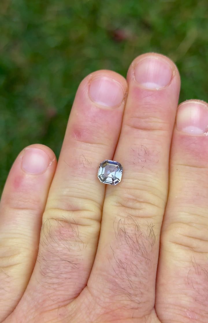 Rotating video of 1.99ct Asscher cut Tanzanite on fingers, capturing a rainbow of pastel tones under natural daylight