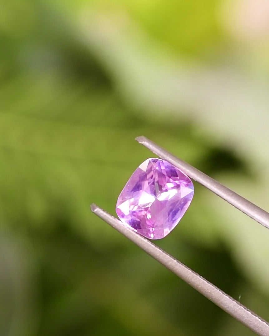 Video of 1.01CT pink sapphire turning in tweezers, revealing vibrant pink brilliance and precision of its cushion brilliant cut, natural untreated gemstone from Madagascar.