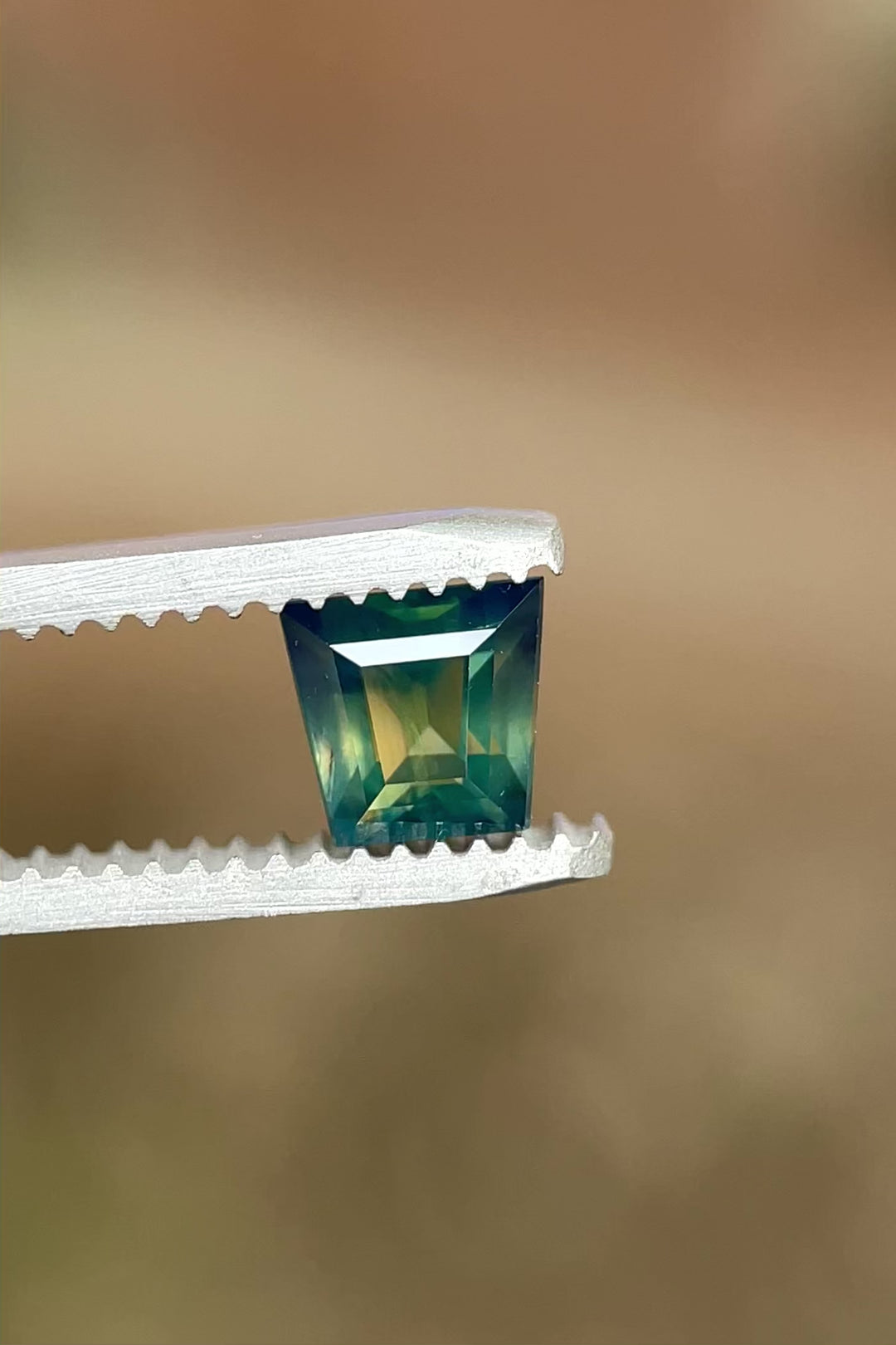 Rotating view of untreated 1.15 carat Australian sapphire showcasing its crisp tapered baguette cut and color zoning

