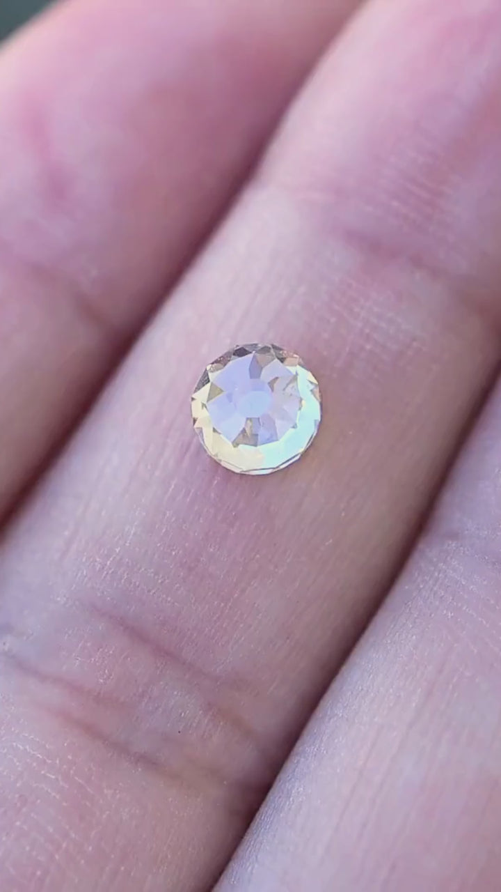 1.11 carat round Mughal cut diamond shown in motion on a hand for scale, with pale champagne, white and cool reflections changing as the stone moves.