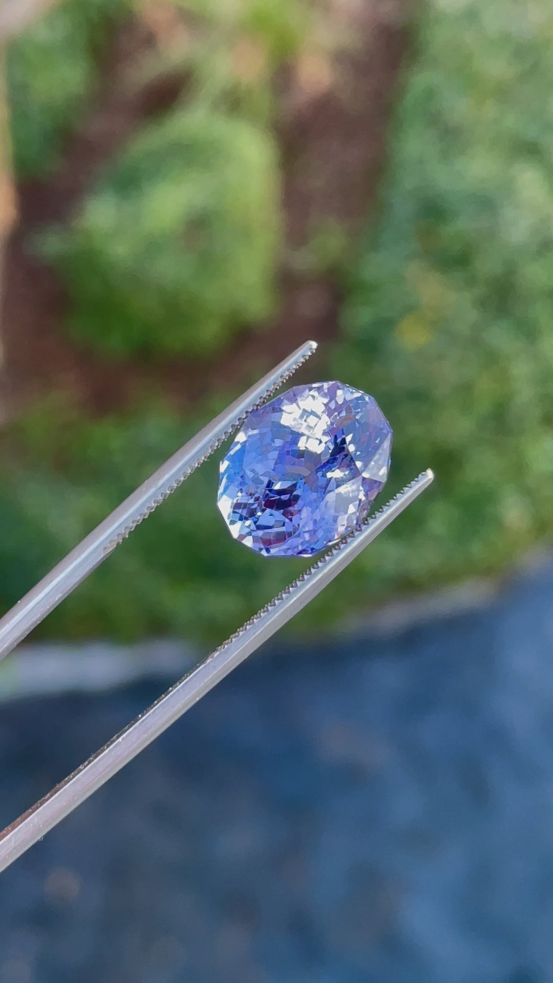 Video of a 9.31-carat tanzanite gemstone in a custom mix cut oval shape, showing its vivid blue and purple hues from various angles.