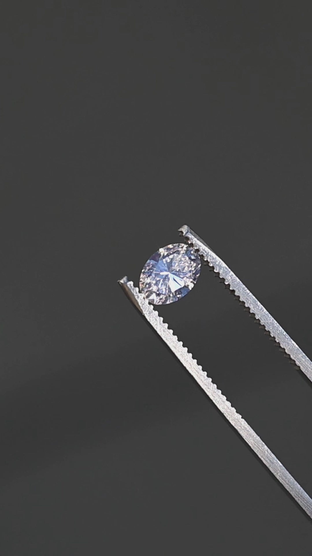 1.04ct champagne oval brilliant cut diamond from Canada rotating in gem tweezers under direct sunlight showing off color and sparkle.