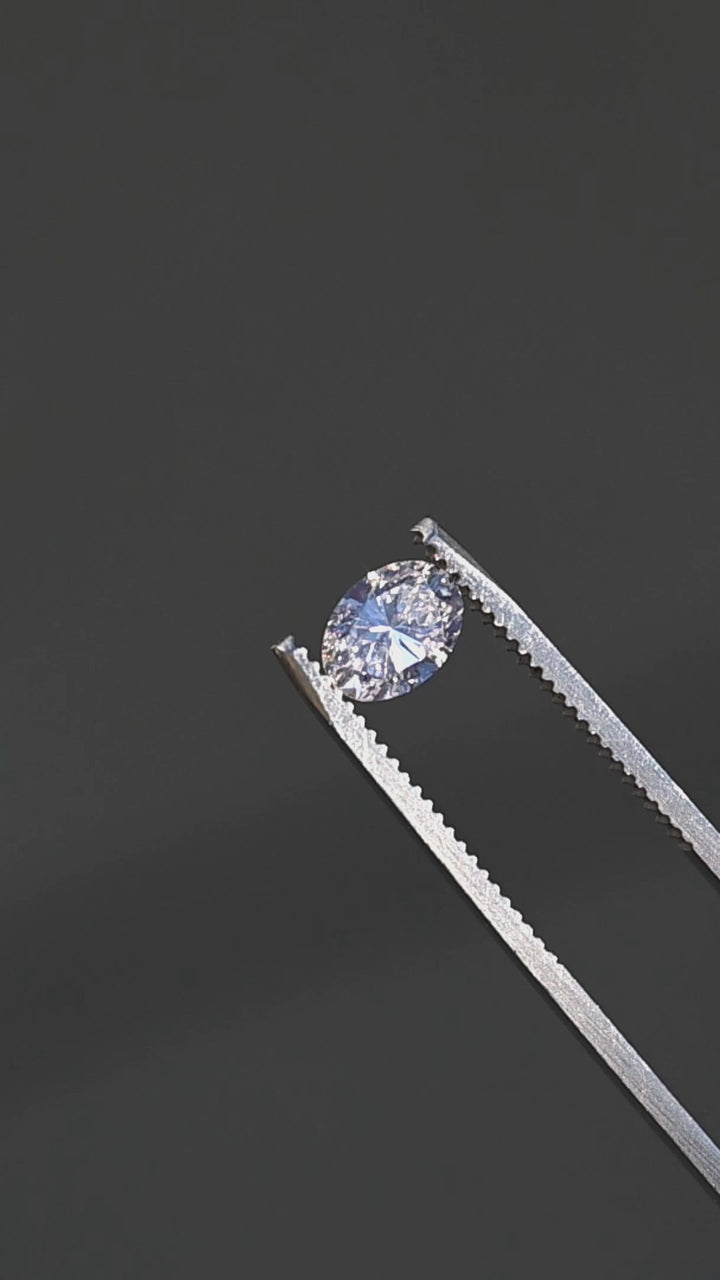 1.04ct champagne oval brilliant cut diamond from Canada rotating in gem tweezers under direct sunlight showing off color and sparkle.