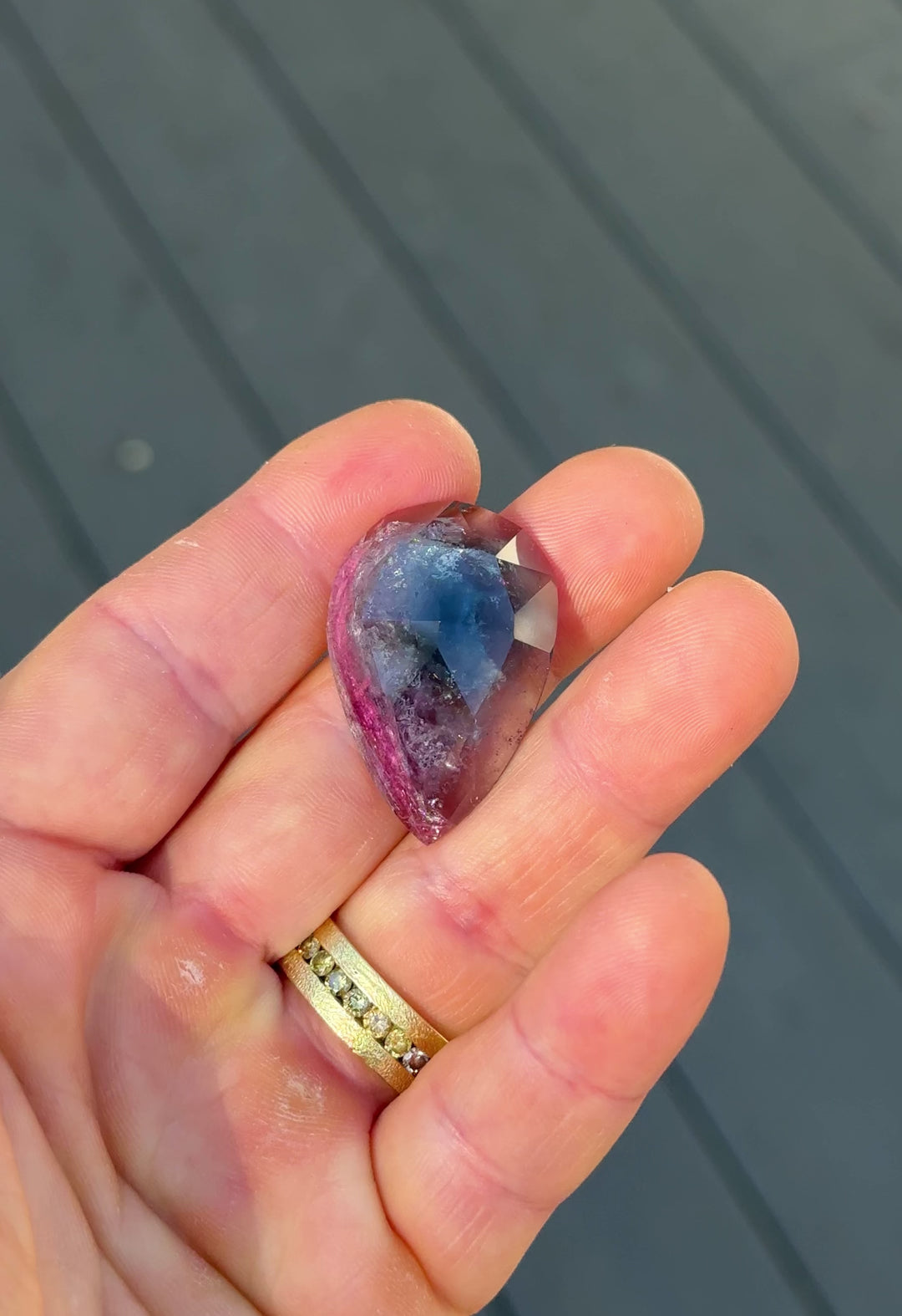 Handheld video of untreated 46.80CT tourmaline gemstone displaying its vivid blue, pink, and purple hues as it moves through natural light, custom pear rose cut from Afghanistan.