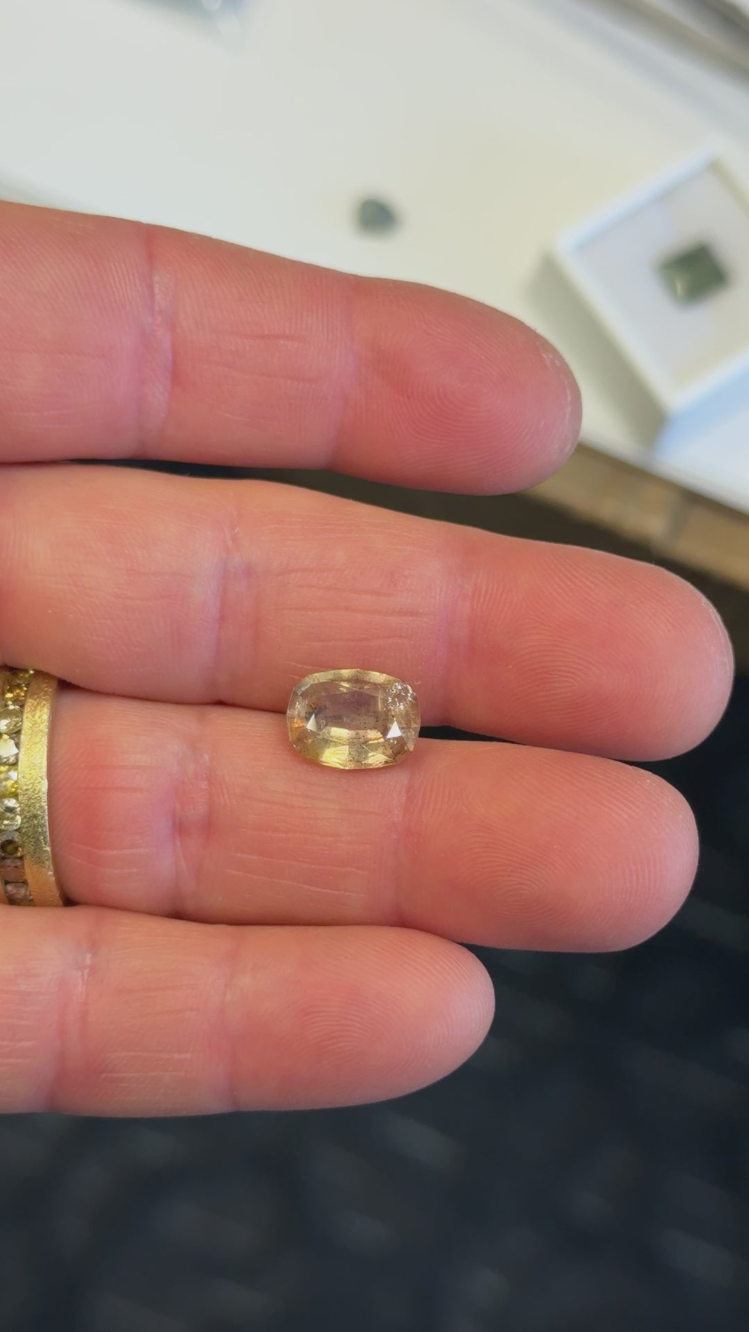  Hand-twisted display of a 4.02-carat Tanzanian sapphire in a custom cushion mixed cut, highlighting its earthy tones and brilliant reflections with natural color zoning and internal character.