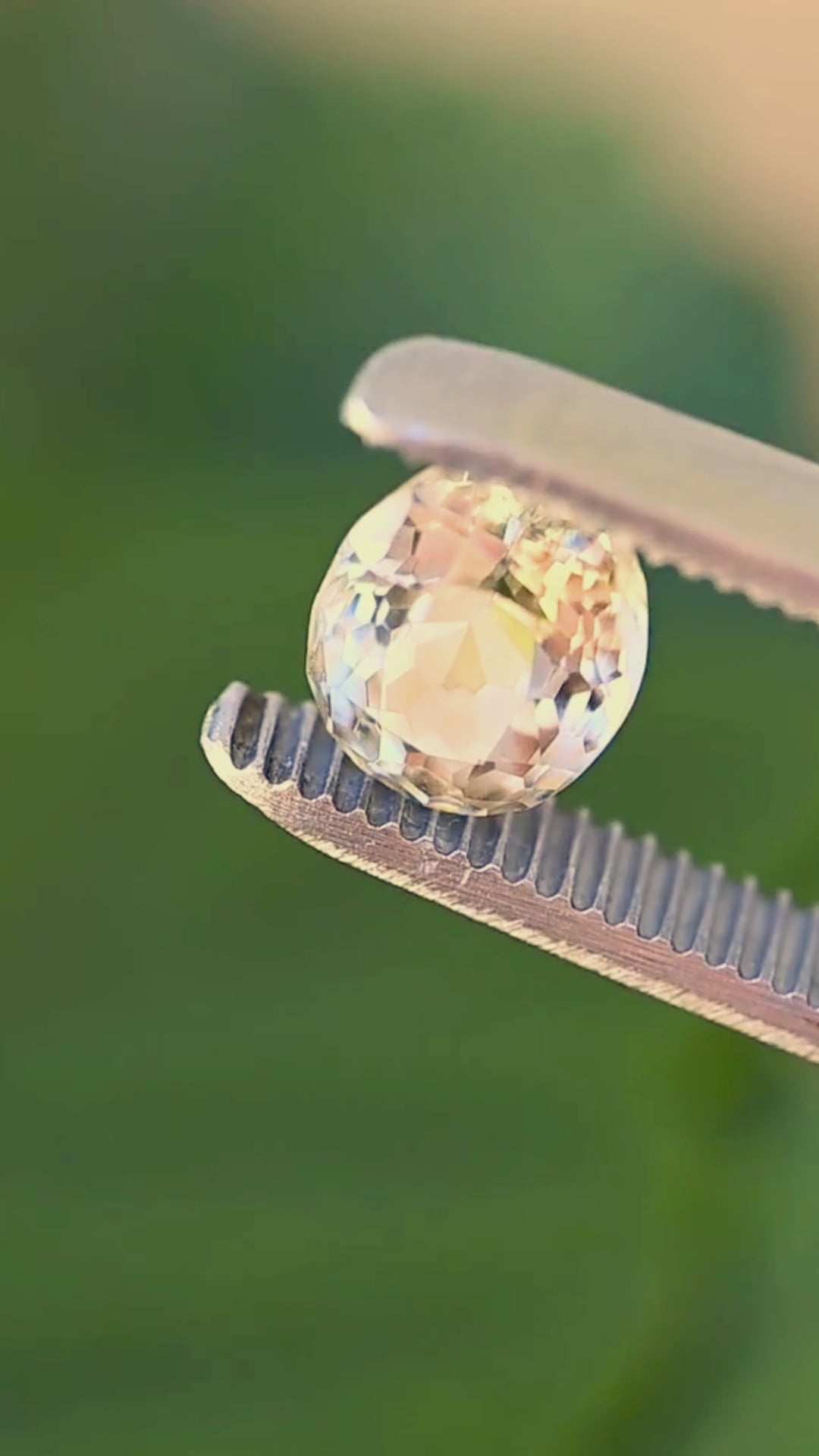 Vintage post-consumer oval-cut yellow tourmaline rotating between jeweler’s tweezers, revealing pale butter yellow, champagne and honey-toned reflections across its mixed faceting.