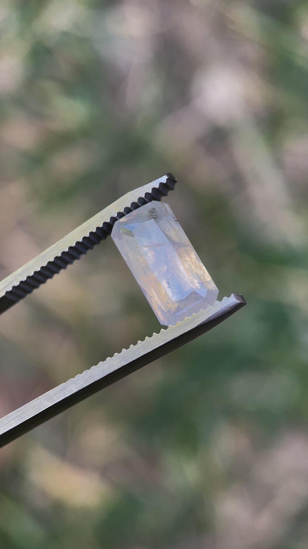 Detailed video of a radiant cut sapphire, weighing 4.18 carats, displaying opalescent white and yellow tones with intricate inclusions.