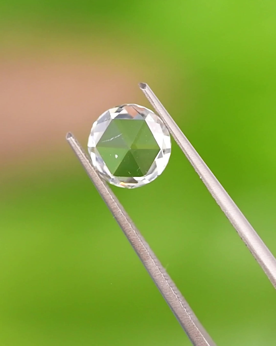 Macro video of a 1.62 carat light green round modified brilliant rose cut diamond from South Africa rotating in tweezers. The GIA certified natural diamond reveals its laser-drilled inclusion, fine symmetry, and radiant sparkle.