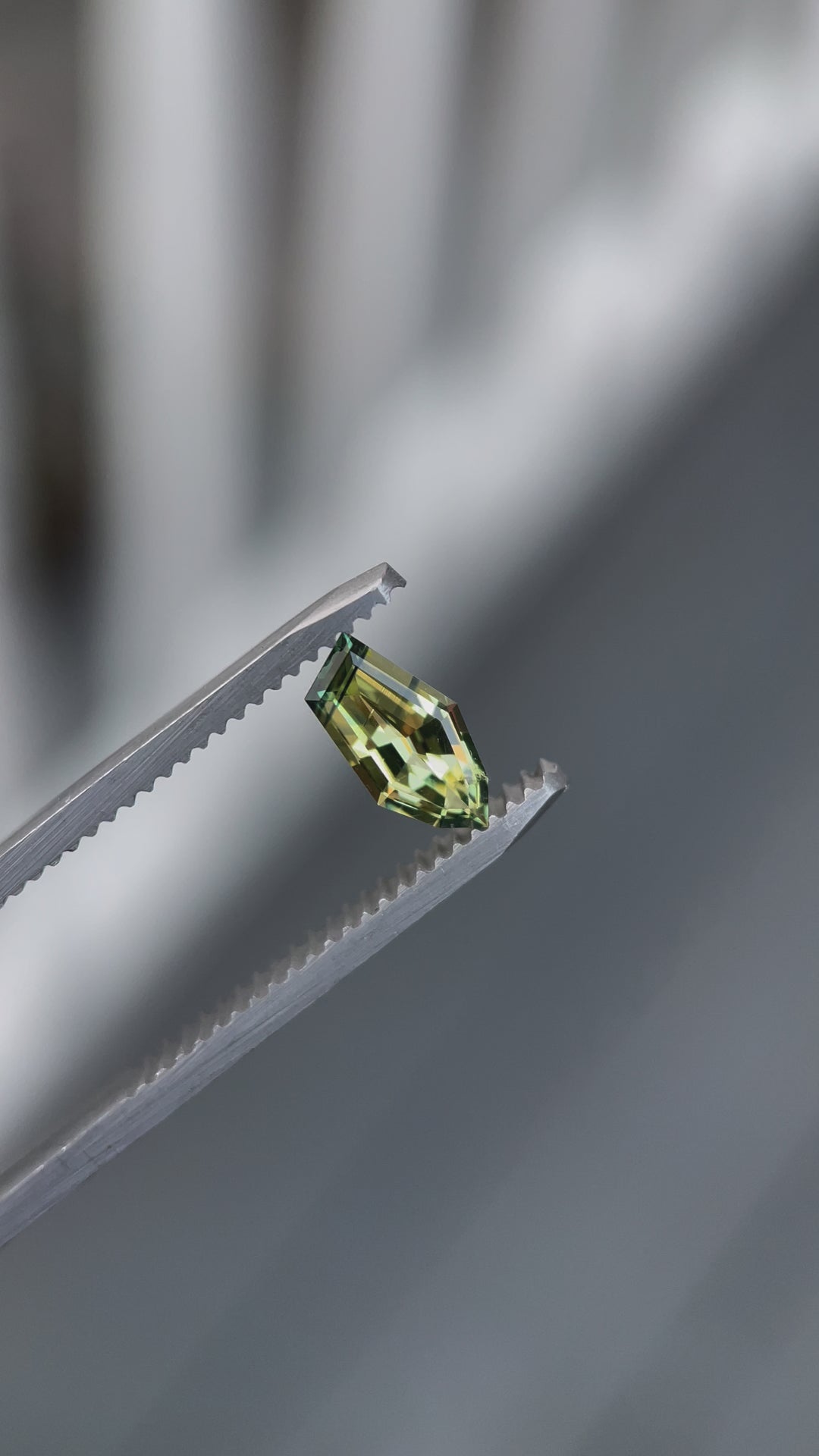 Video showcasing a 0.80-carat yellow-blue sapphire with a freeform geometric cut. The gemstone, sourced from Gombe, Nigeria, is displayed in motion to highlight its vivid color transition and natural, untreated qualities under different lighting conditions.