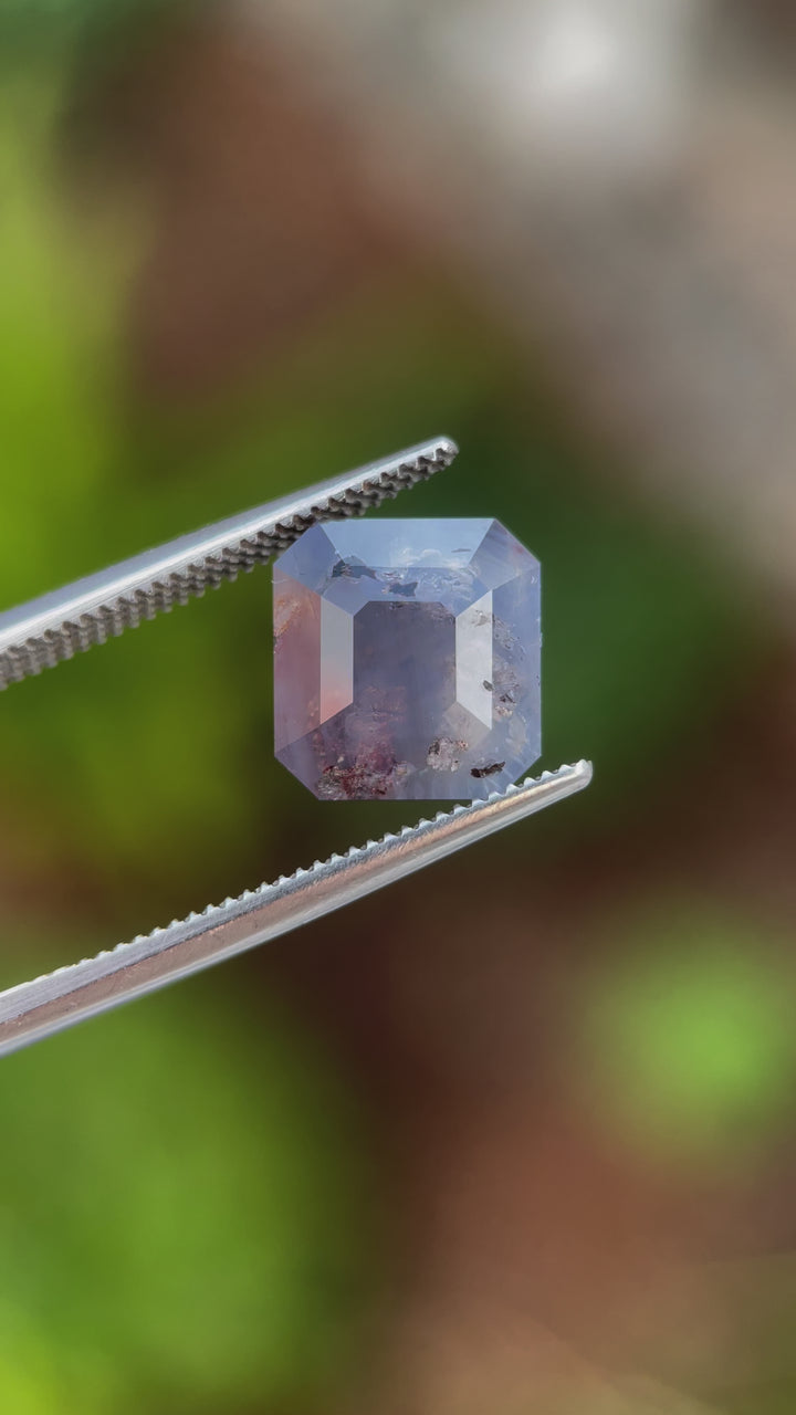 A rotating view of a 5.92-carat emerald cut sapphire, highlighting its faceted edges, unique coloration, and natural beauty in detail.