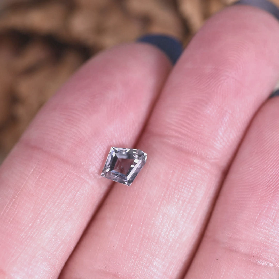 Video of 0.98ct Montana sapphire on hand rotating under light, gray violet teal custom modified kite step cut showing color shift and step facet reflections