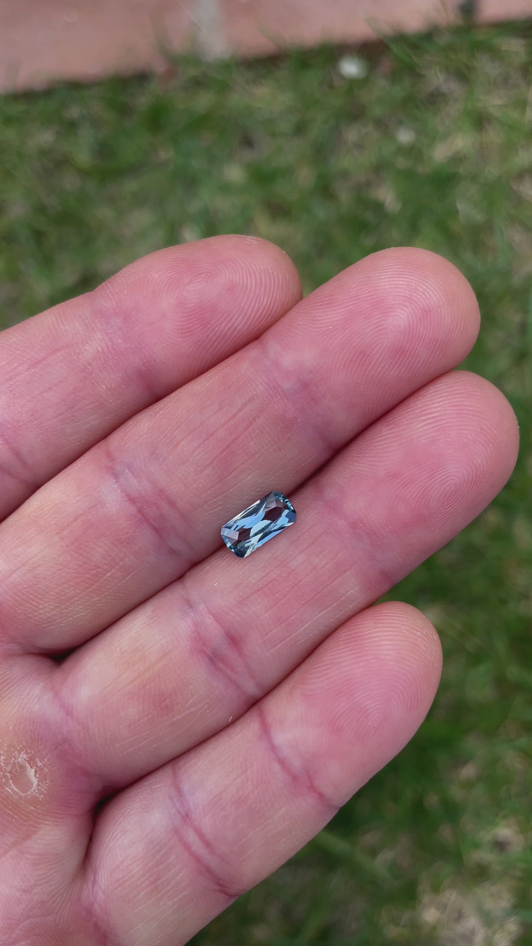 A close-up video of a blue sapphire with an elongated geometric cushion cut, showcasing its facets and reflections. The gemstone weighs 1.26 carats and originates from the Umba River, Tanzania.