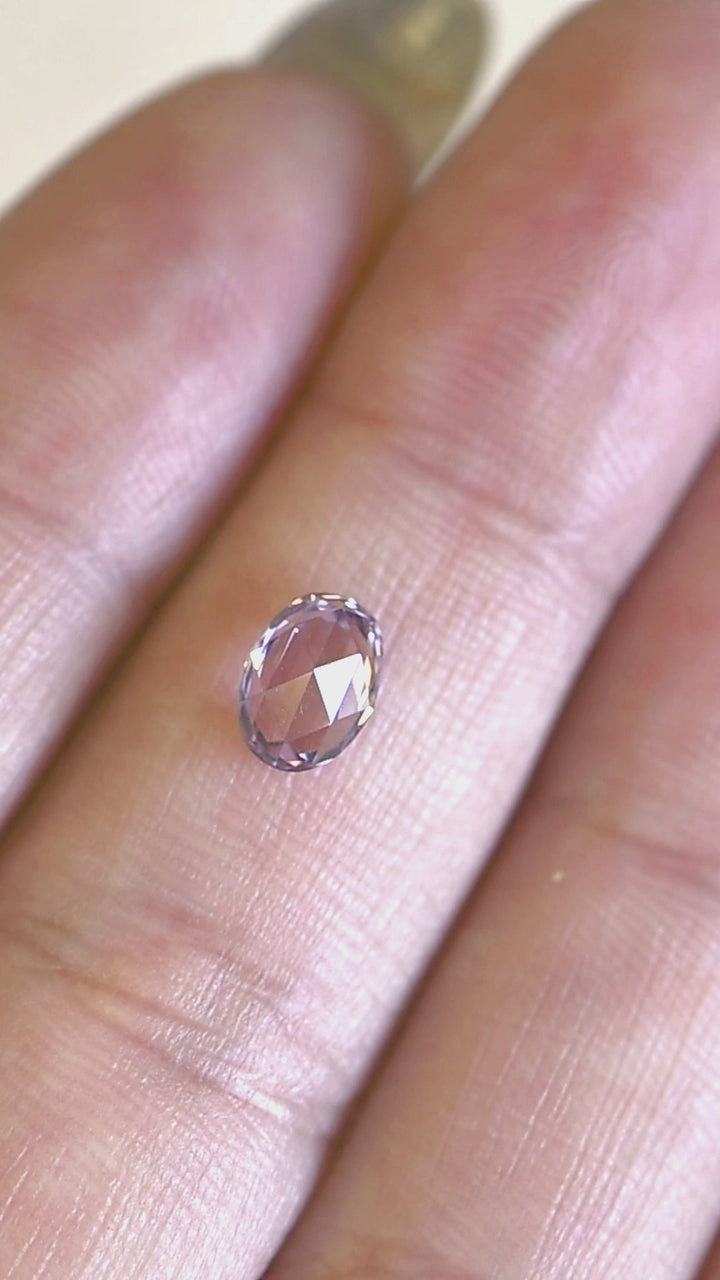 1.18ct lavender pink sapphire rotating in hand, revealing soft rose and lavender flashes across the precision oval rose cut.